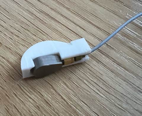 Ein kleiner weißer Gegenstand mit einem Metallgegenstand, der an einem Draht befestigt ist
KI-generierte Inhalte können falsch sein.